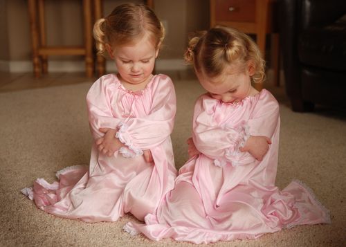 Twin toddler girls praying.