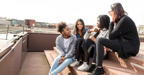 A group of young woman sit outside and socialize.