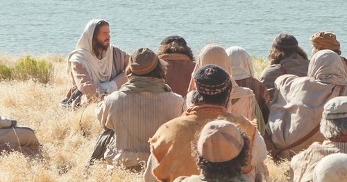 Jesus is in the background with the group sitting in the foreground.