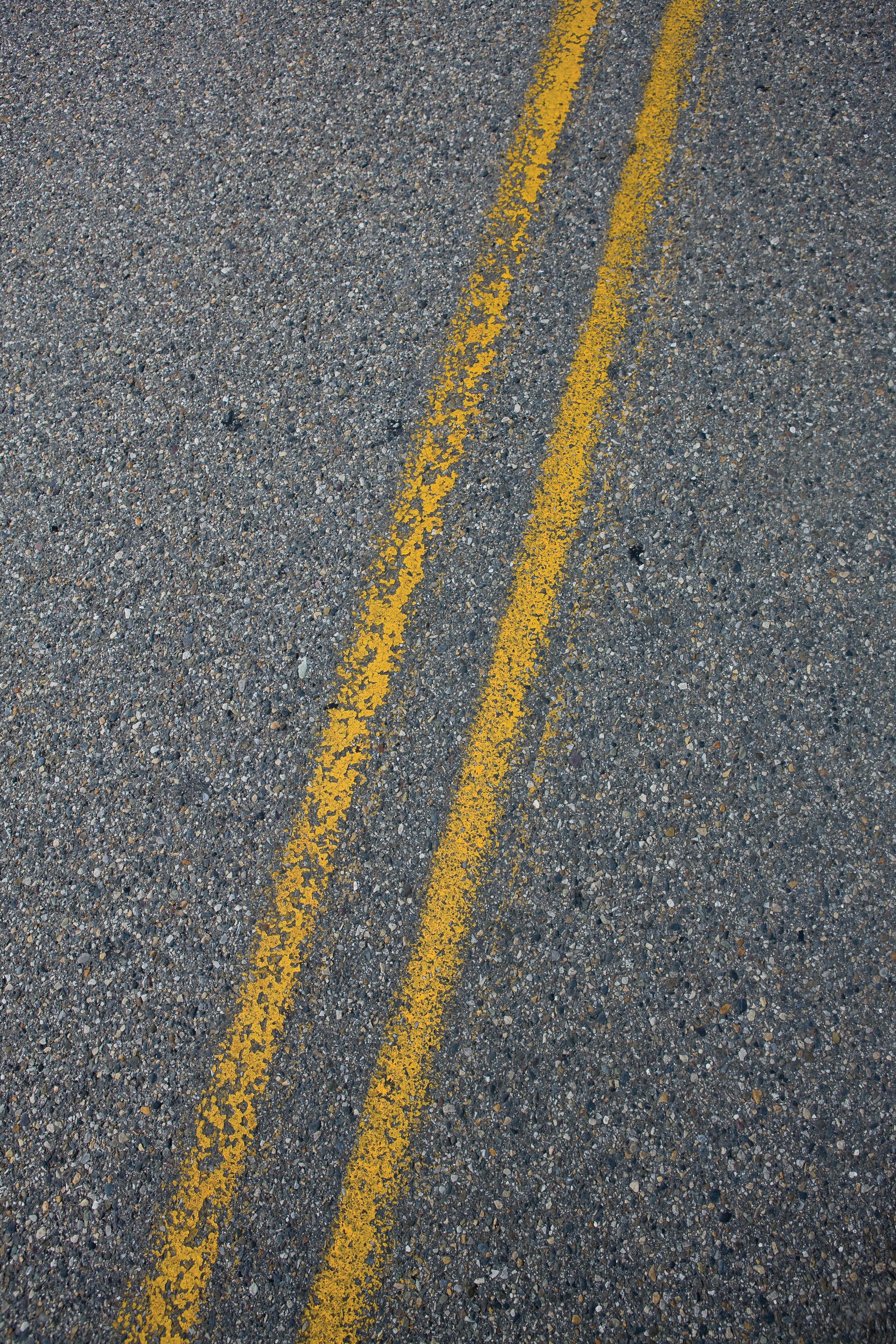 A painted double yellow line on an asphalt road.