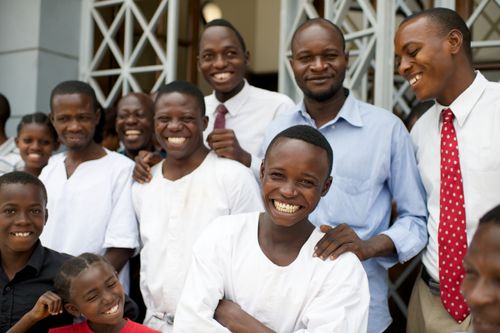 A large group of people, some of whom are dressed in baptismal clothing, smiling together.