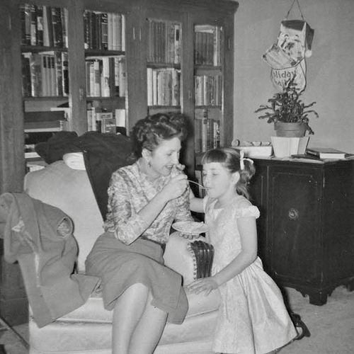 a mother feeding her daughter out of a dish