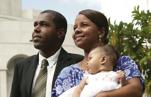 A Brazilian family standing outside of the Recife Brazil Temple which is in the background.
