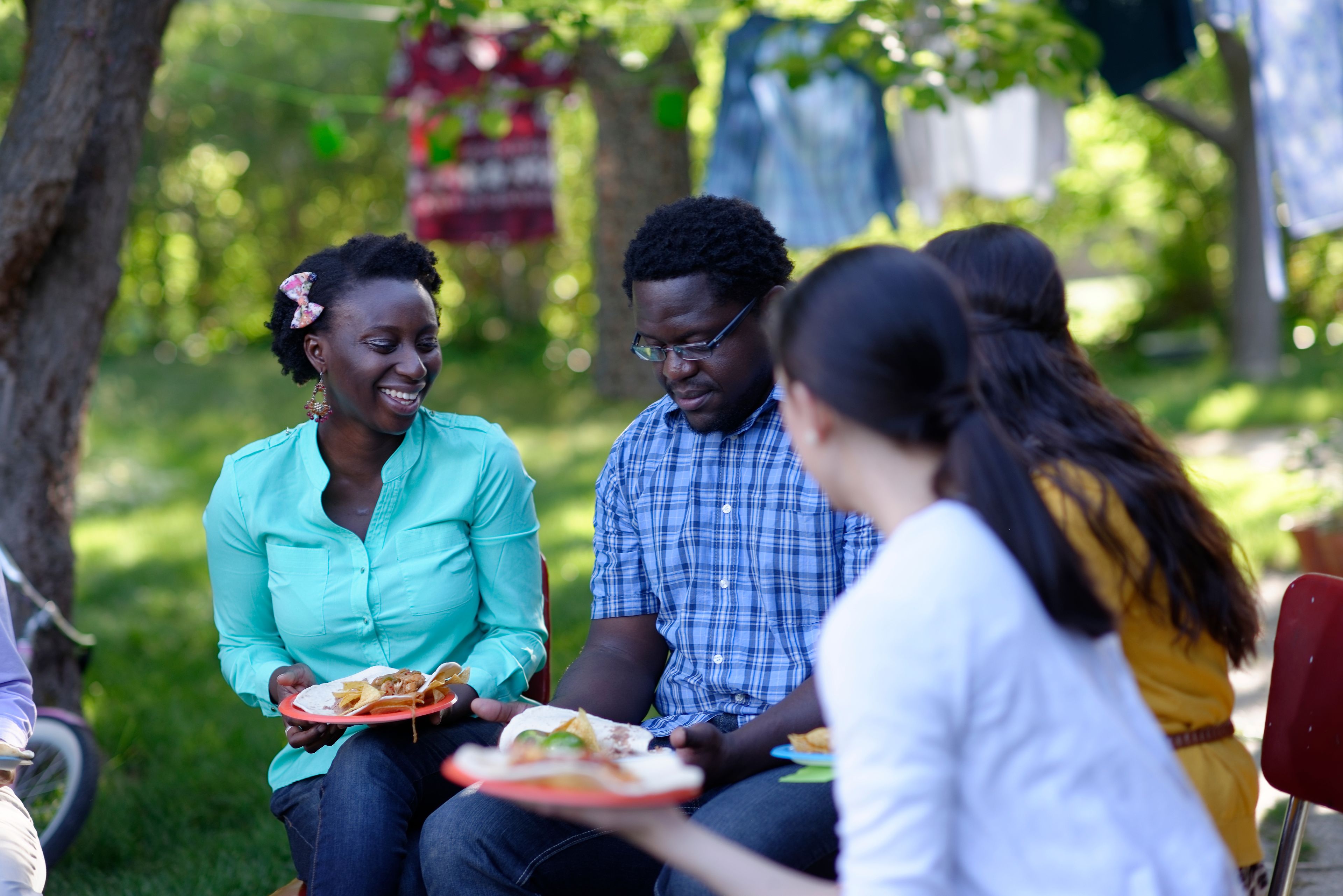 Some young adults sit together and eat at a picnic.