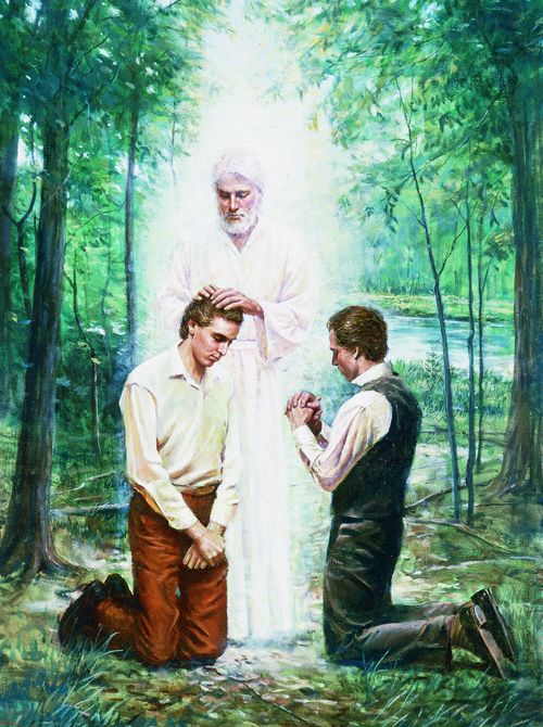 Joseph Smith, Jr. and Oliver Cowdery kneeling before John the Baptist. John the Baptist has his hands placed on the head of Joseph Smith, Jr. as he restores the Aaronic Priesthood. John is depicted wearing white. There are trees and a river in the background.