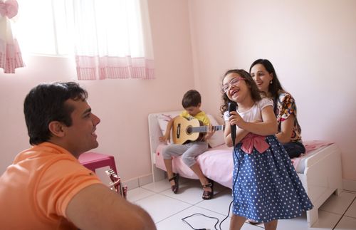 Young family in Brazil read together, parents teach children with drawings, they sing together, mother reading, father holding up chart etc.