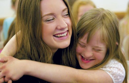 Primary teacher hugging child with Down syndrome