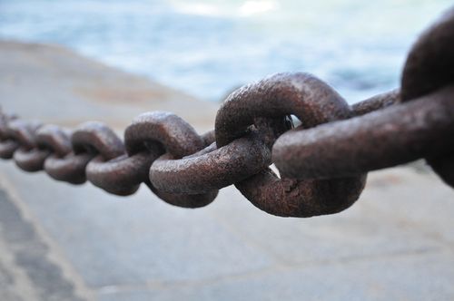 A close-up view of a metal chain hanging near the seashore.