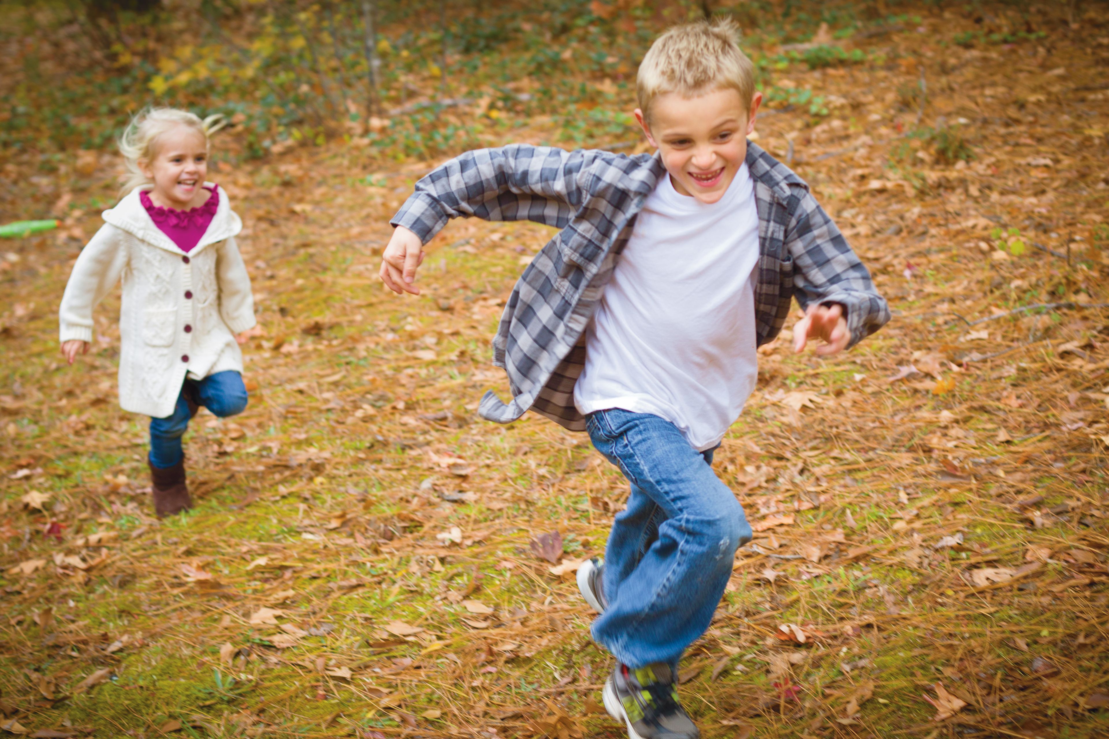 A brother and sister play outside together.
