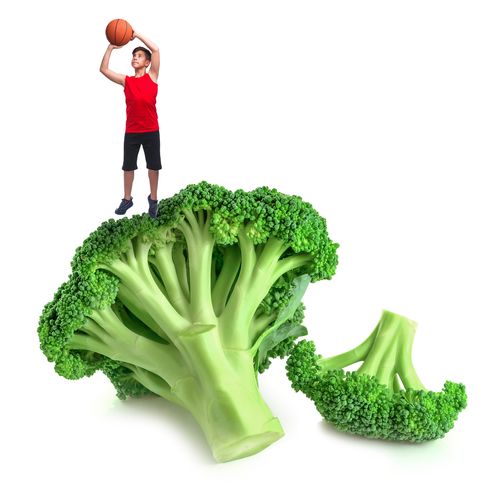 boy shooting basketball over large broccoli