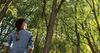 a woman looks up at trees