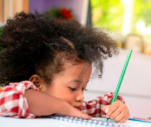 Νεαρό κορίτσι χρωματίζει στο σημειωματάριο