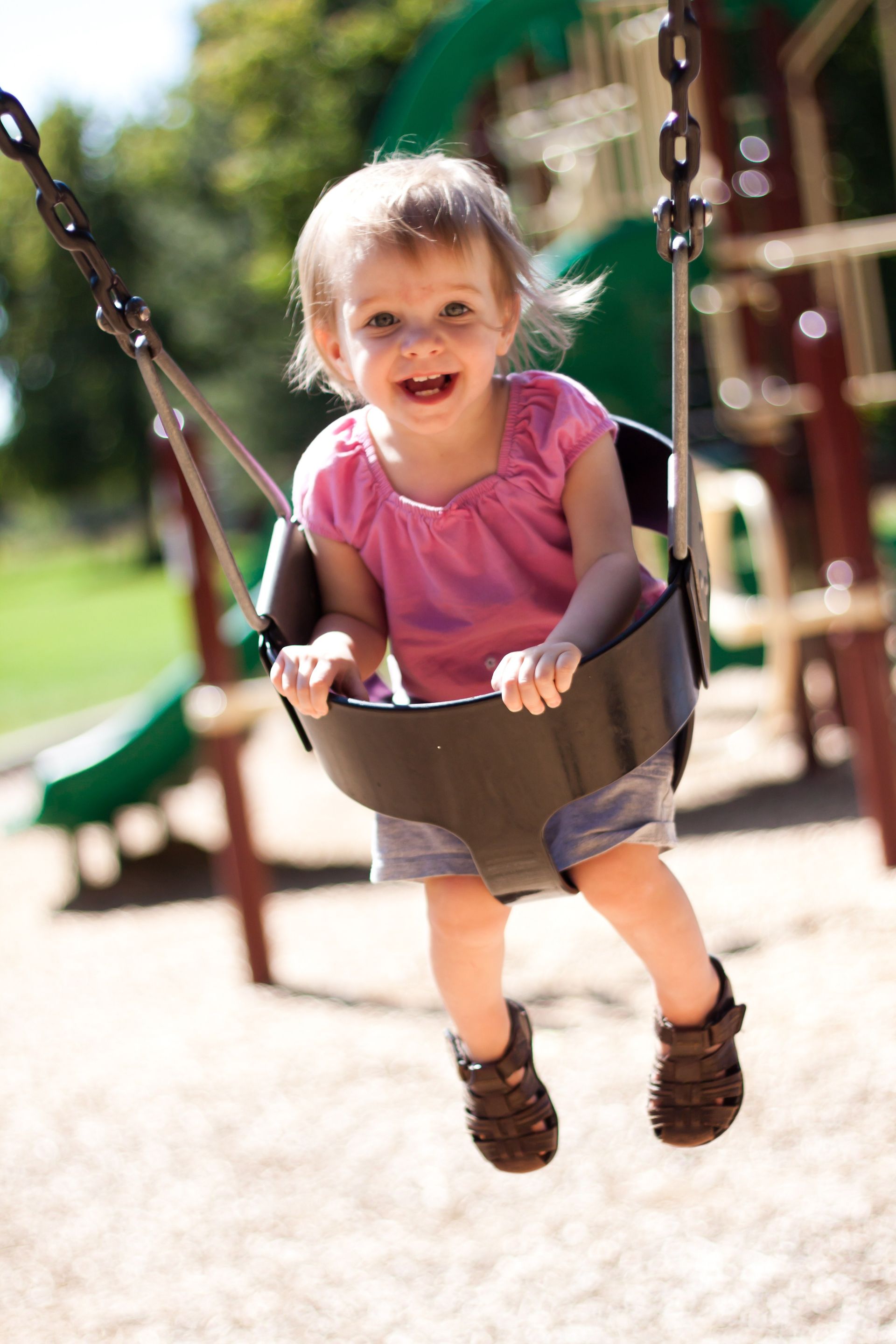 A young toddler swinging.