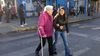 young woman helping older woman cross the street