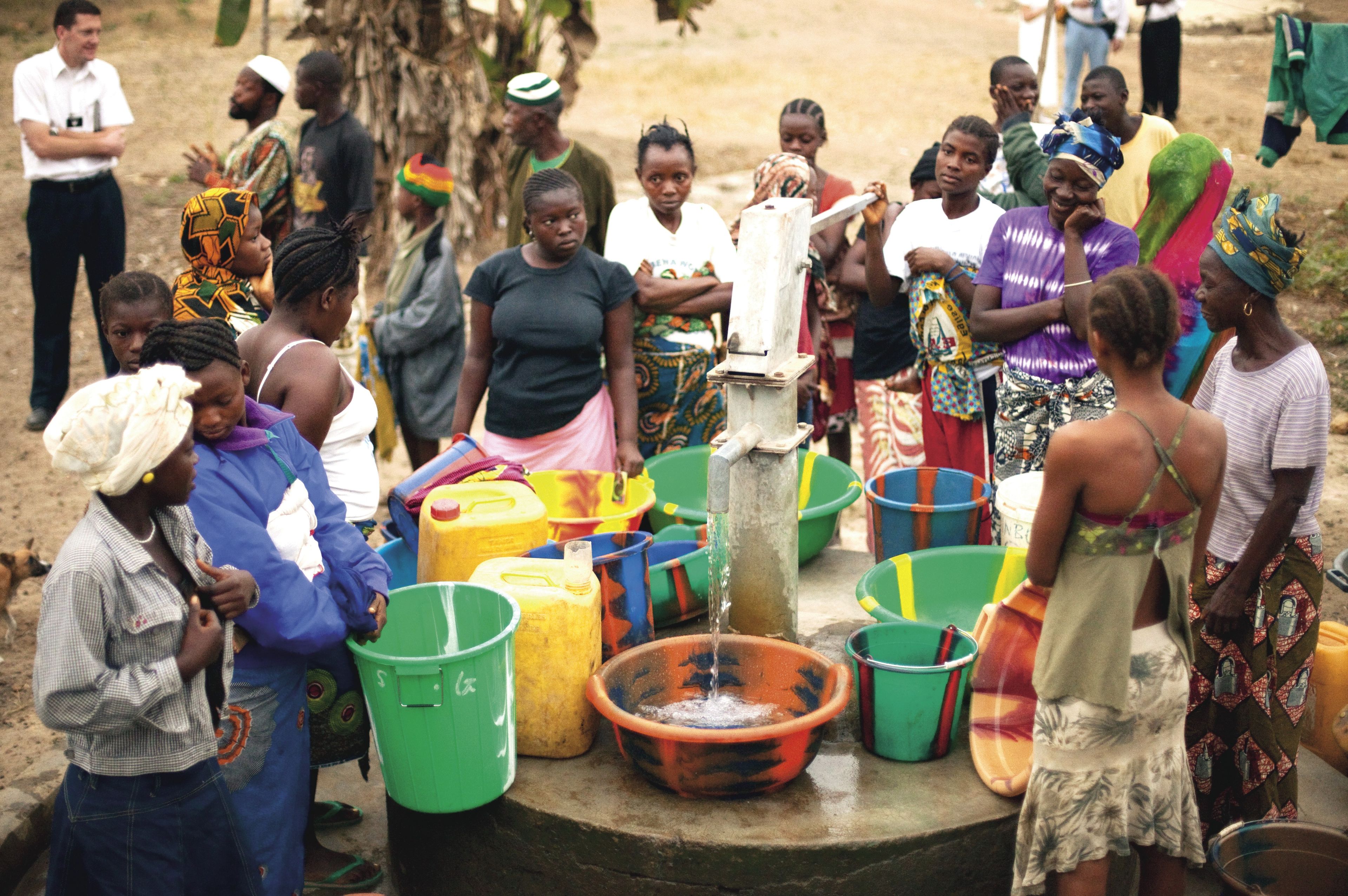 A group of people in Africa waiting to use the hand-operated water pump.