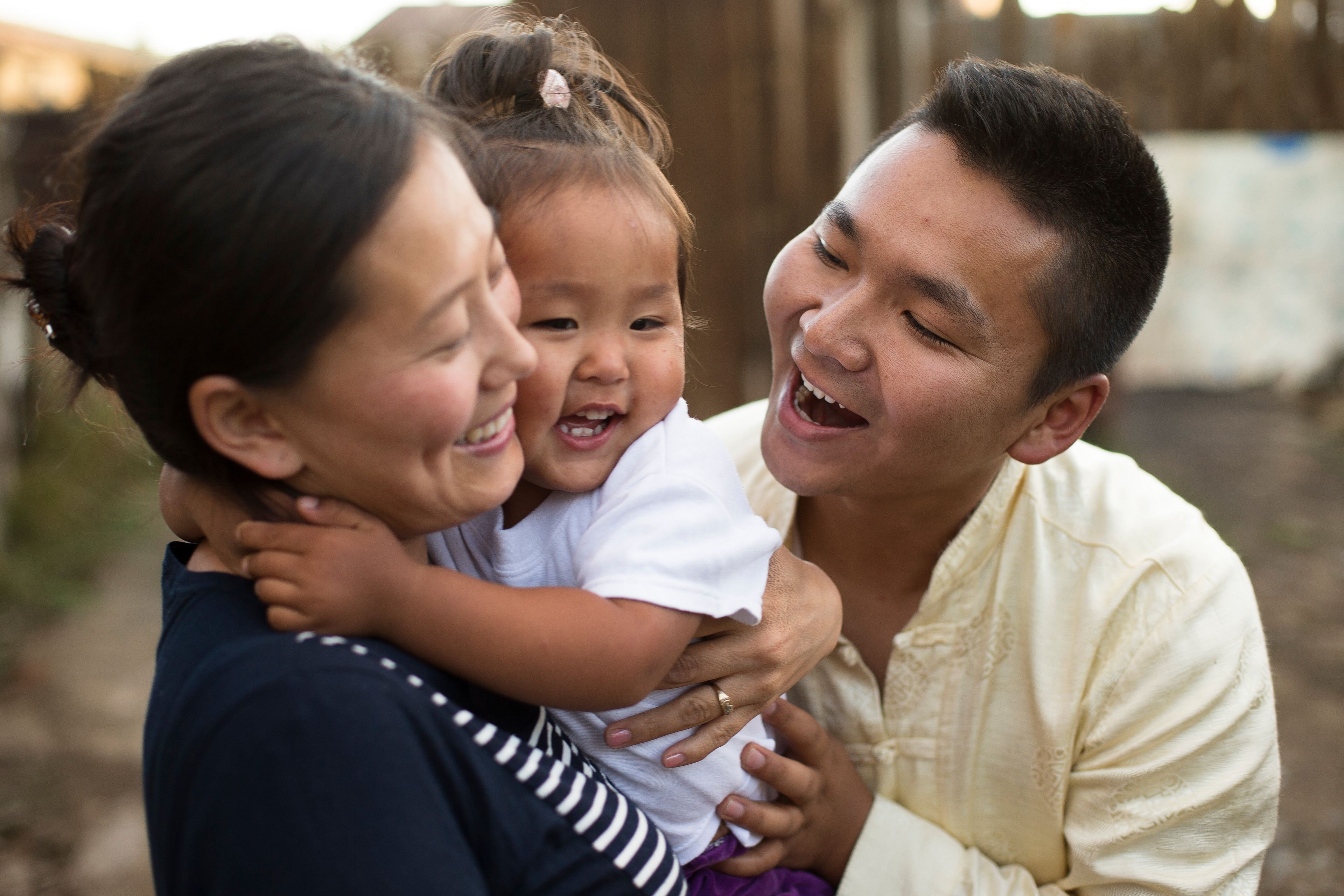 A young family in Mongolia laugh together in a happy moment.
