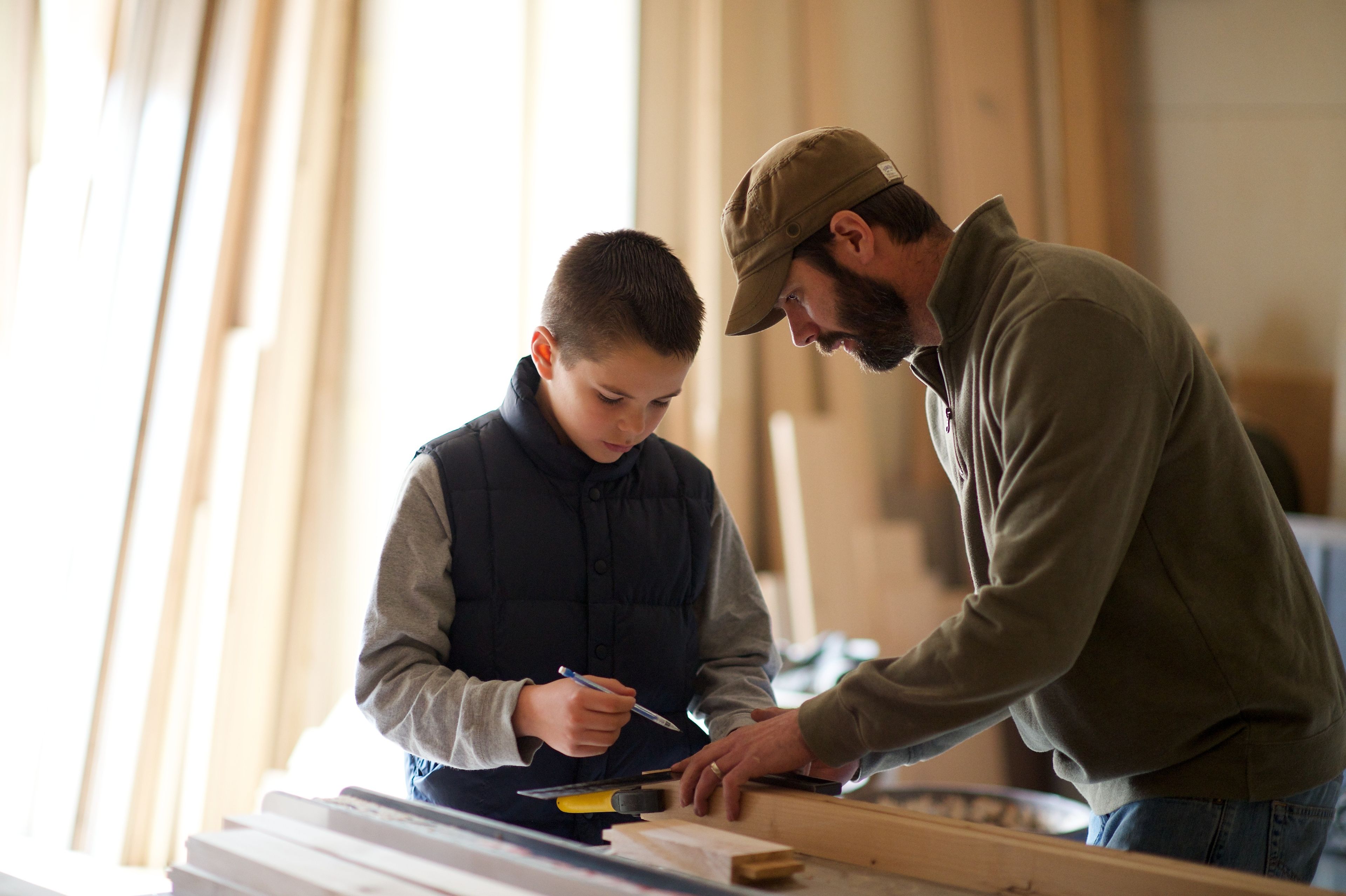 A father shows his son how to do some woodworking.