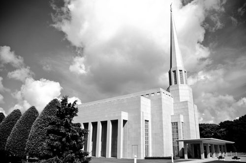A side view of the Preston England Temple in black and white, with manicured bushes and trees growing on the grounds.