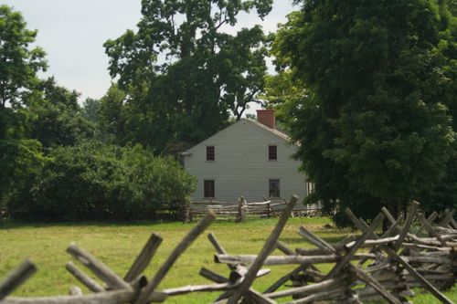 Wooden fences in the foreground and a white wooden-frame home in the background in Palmyra.