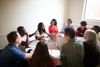 A group of diverse middle-aged adults gather together and greet one another. They appear to be a support group helping with addiction.