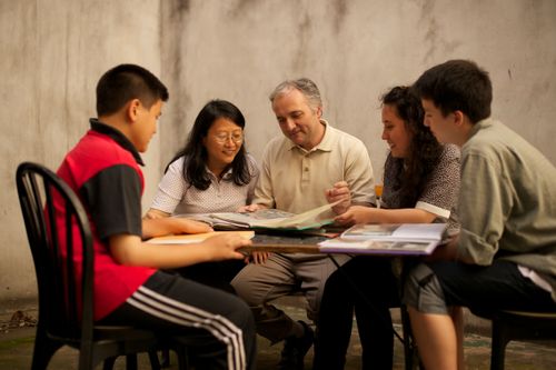 A father, mother, daughter, and two sons from Argentina sit at a table and look through family history documents.