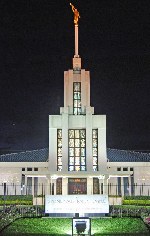 The front of the Sydney Australia Temple, with the spire, stained-glass windows, doors, and temple name sign.