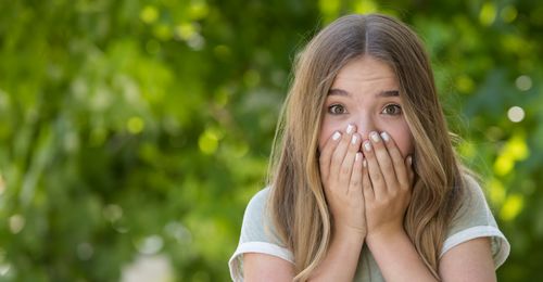 Young woman with hands over mouth