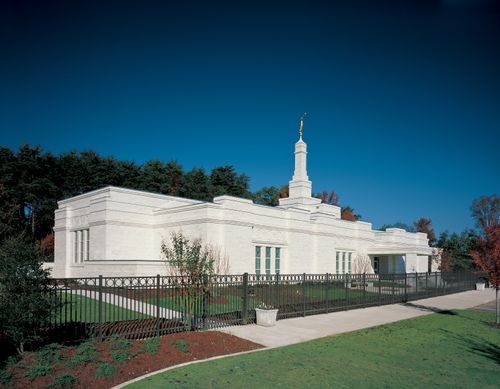 Grass, trees, and a black fence surrounding the Birmingham Alabama Temple.