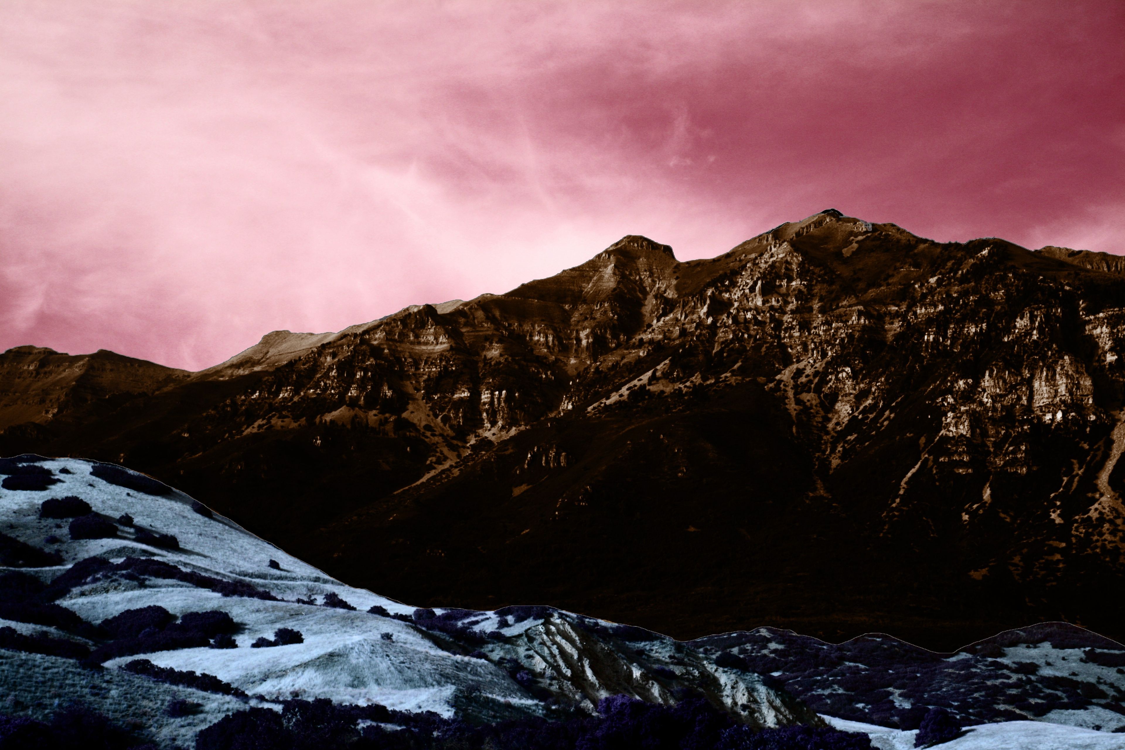 A pink sky hangs over a mountain range.
