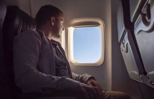 young man looking out airplane window