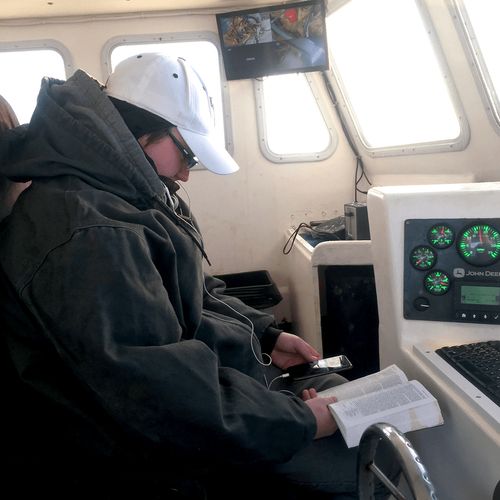 young man reading scriptures in a boat