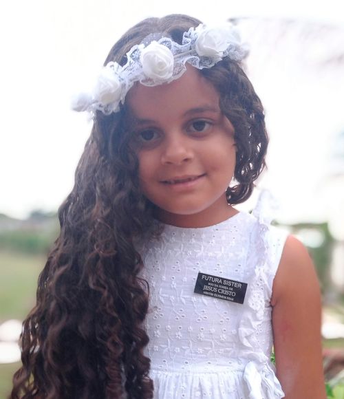 Melissa Evangelista de Barros smiles for a picture. She is wearing a paper missionary name tag.