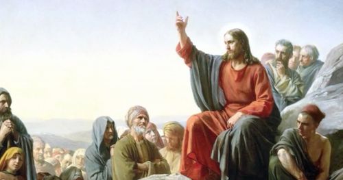 Jesucristo predicando a una multitud de personas. Cristo está sentado en una colina rocosa. Está vestido con túnicas rojas y azules. Tiene un brazo levantado. Algunas de las figuras tienen las manos juntas en señal de devoción.