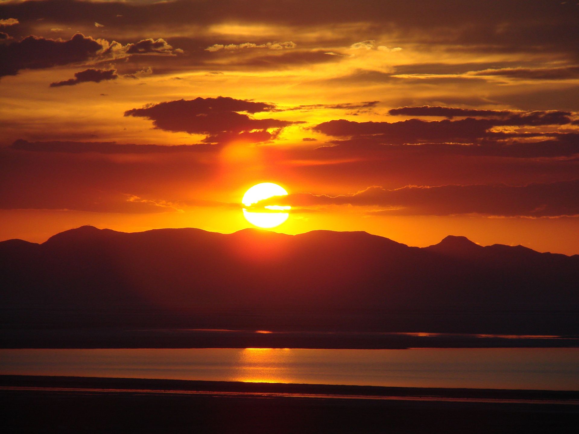 The sun sets behind mountains and the Great Salt Lake.