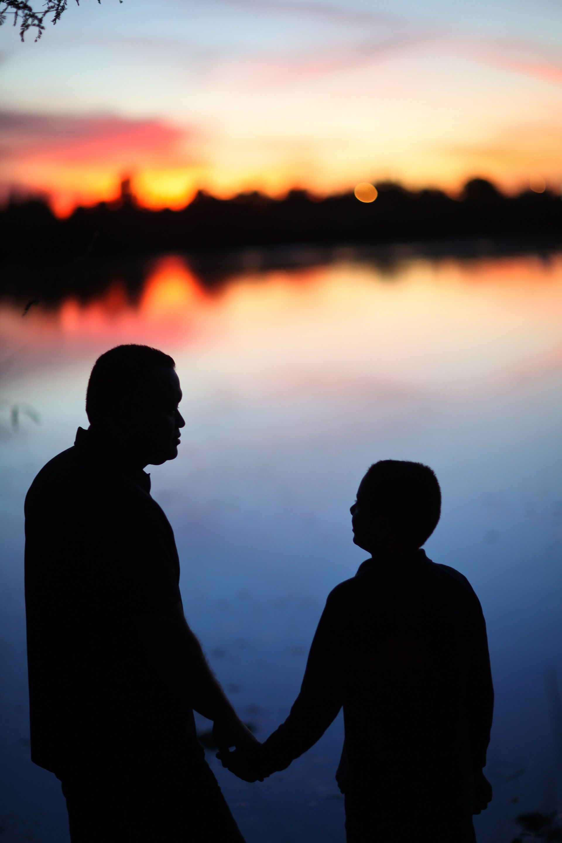 A father and son walk around a lake at sunset.