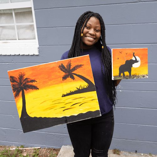 young woman holding up paintings