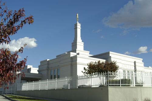 An exterior view of the Bismarck North Dakota Temple during the day, with the temple’s white fence around the temple grounds.