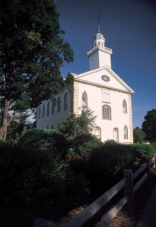 A view of the Kirtland Temple from the bottom of the hill, with a clear blue sky behind the spire.