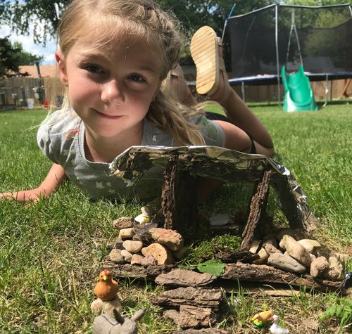 A young girl lies on the ground next to a small stable that is meant to be a nativity scene.