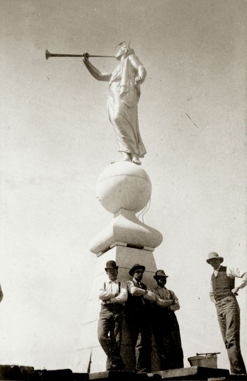 estatua del ángel Moroni con cuatro obreros junto a la base