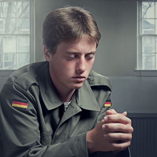 Photo illustration depicting Jorg Klebingat in military uniform.  He is praying.