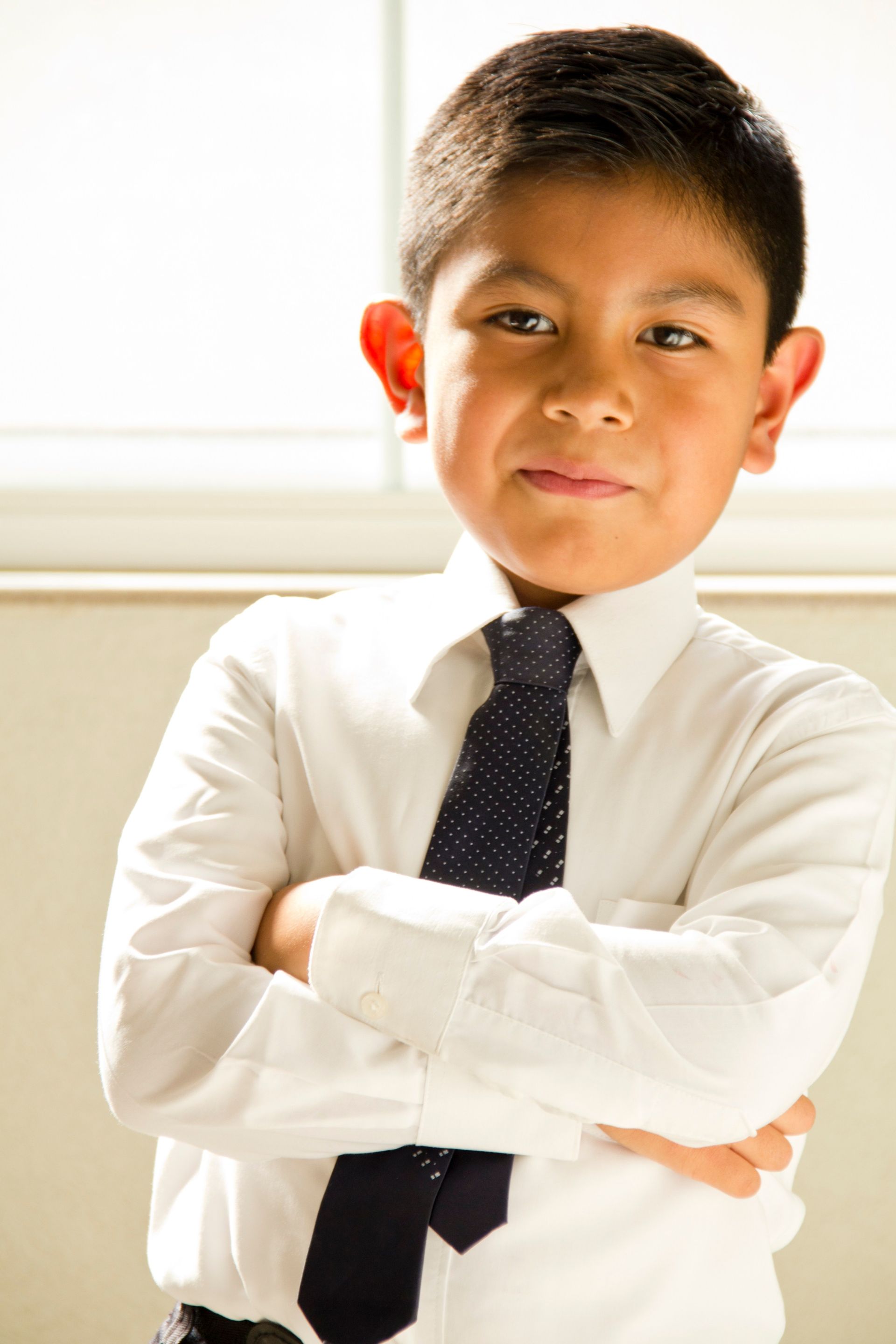 A portrait of a young boy folding his arms at church.