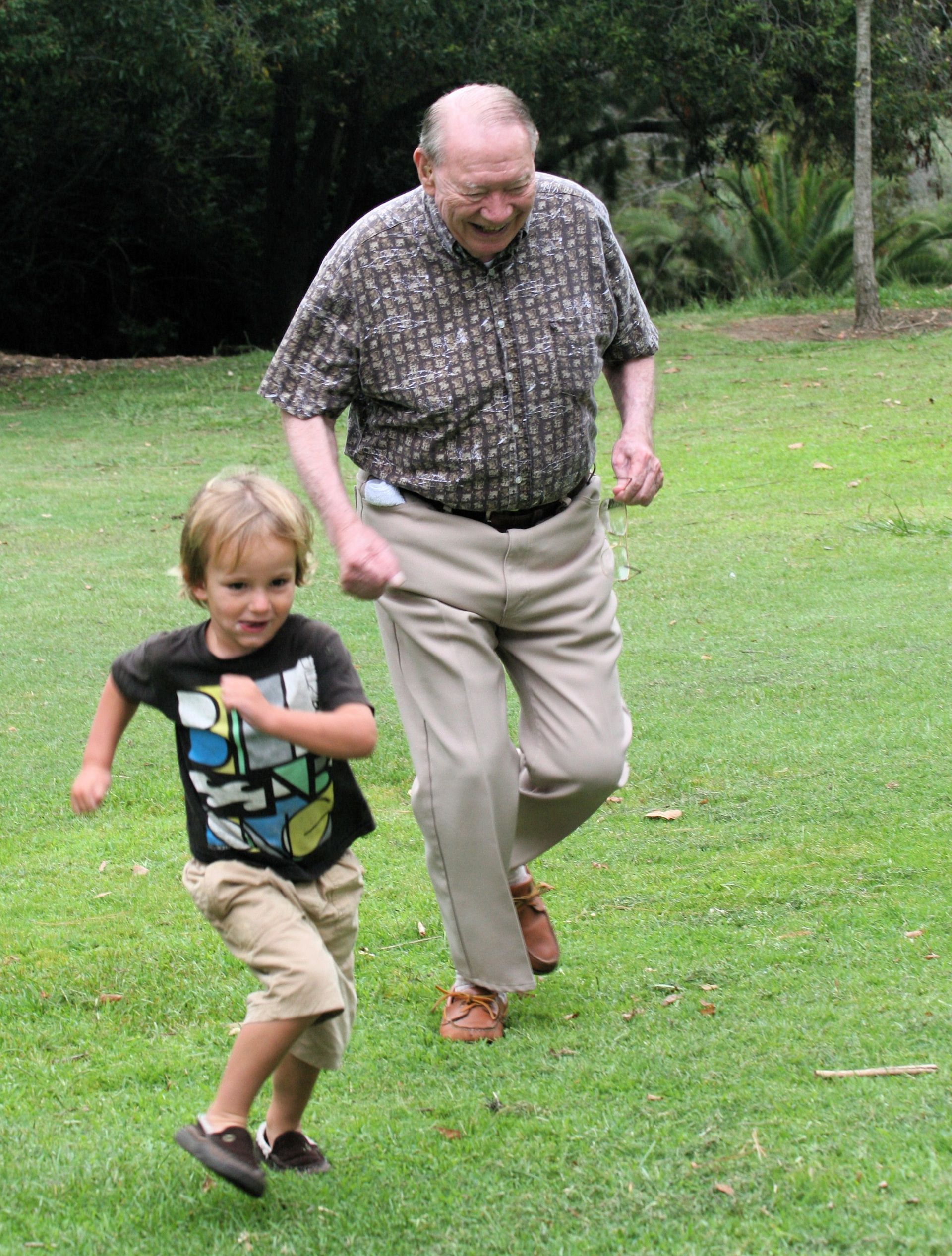 A young boy plays with his grandpa outside.