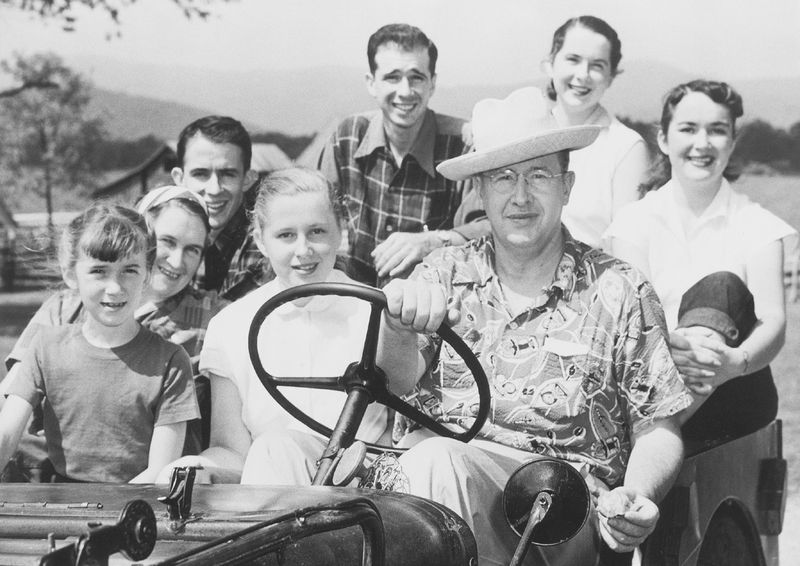 President Benson sitting behind the steering wheel of a car with his children.