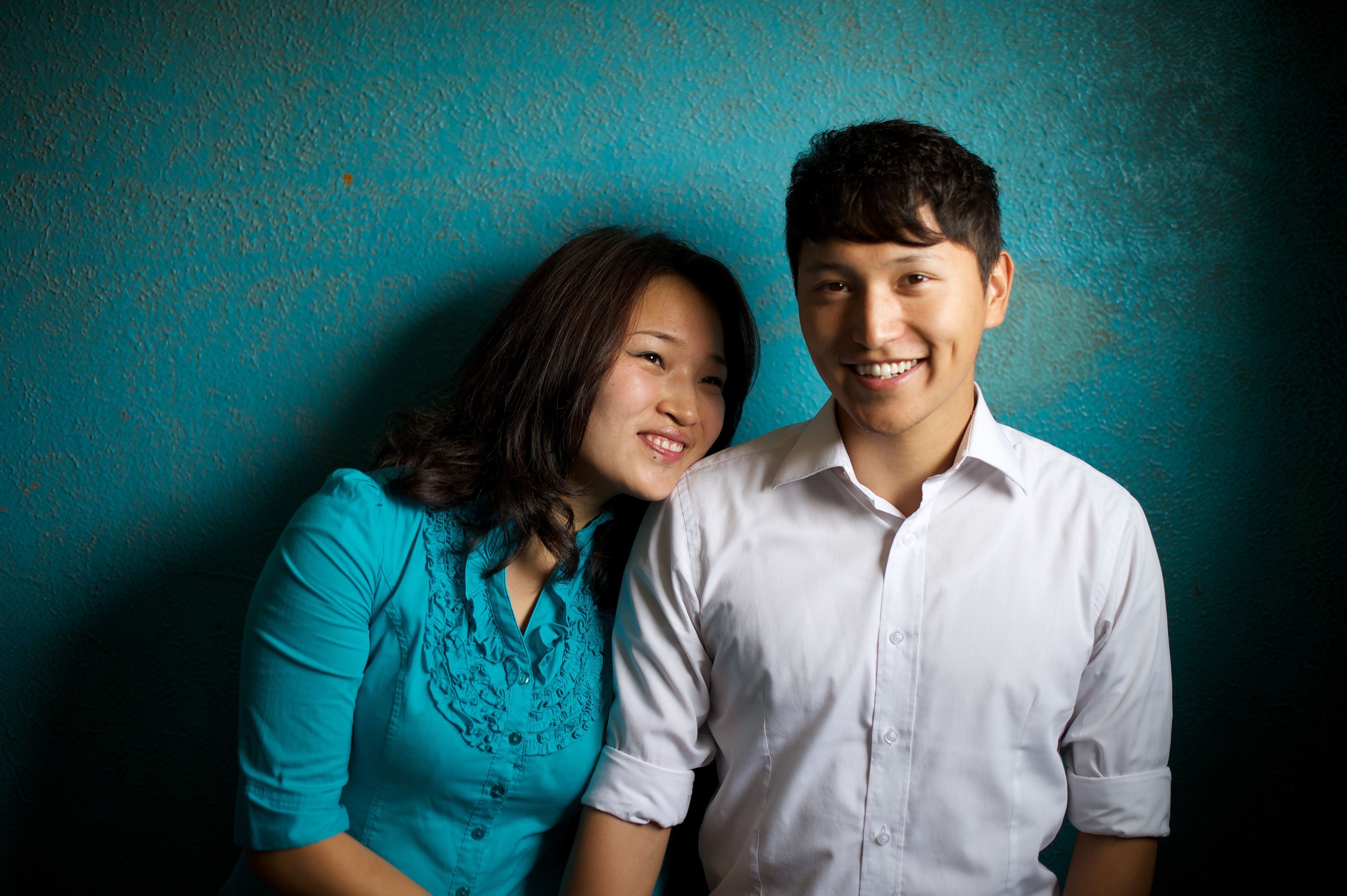 A portrait of a young couple from Mongolia, with a blue background.