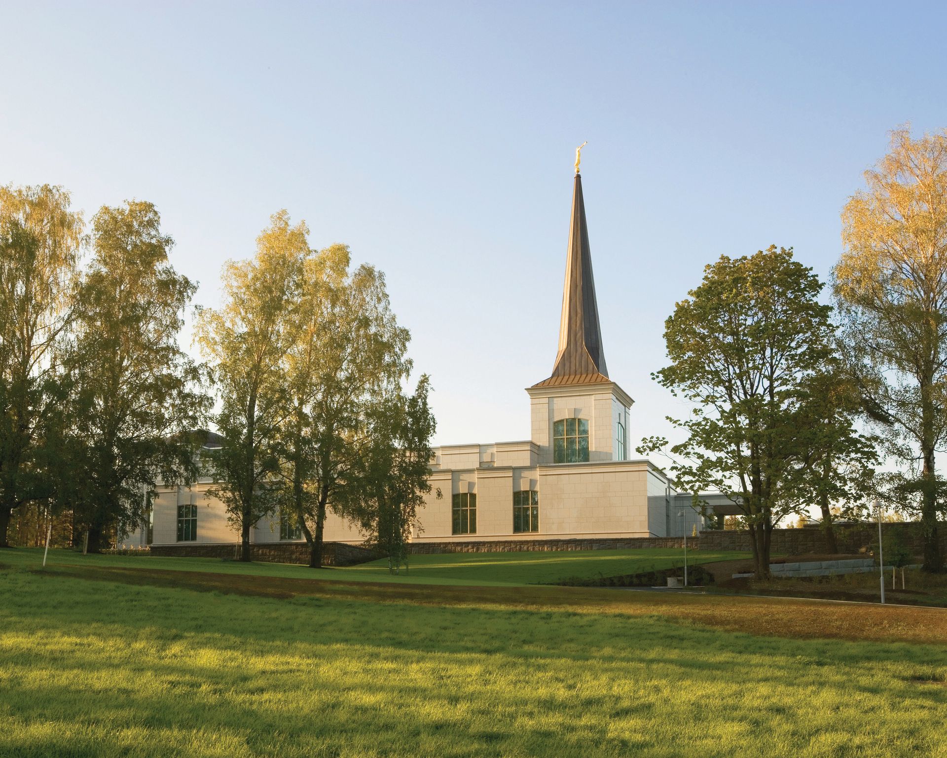 An exterior view of the Helsinki Finland Temple and grounds at sunset.