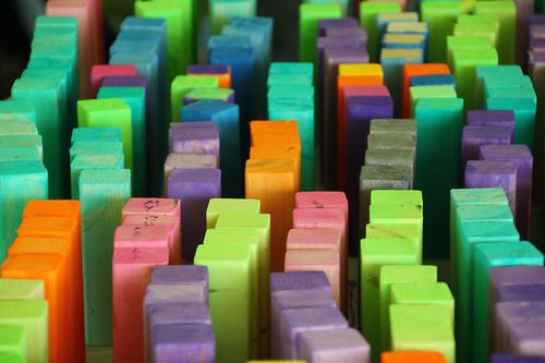 Small wooden pieces painted green, purple, blue, orange, and pink standing on end in messy rows.