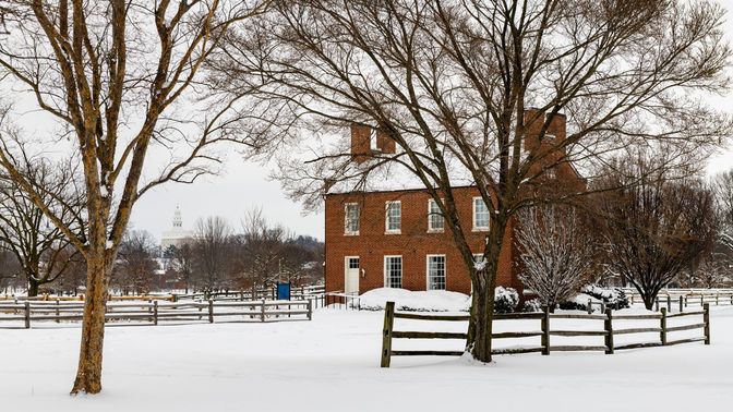 Snow-covered streetscape with a red brick building covered in snow in the background.