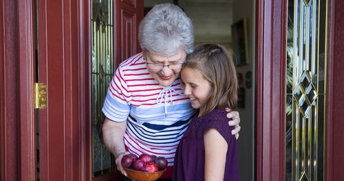 girl sharing fruit with elderly woman