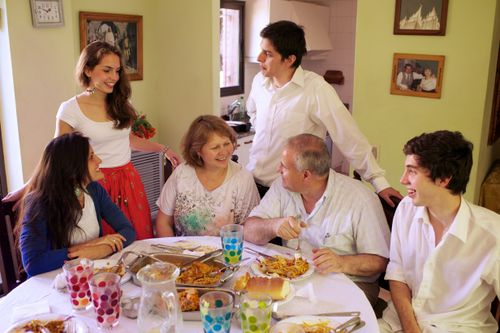 A mother and father sit at the dinner table with their four teenage children.